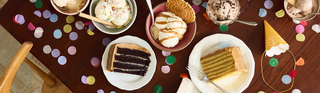 Bowls of ice cream with pizzelle cookies beside chocolate and caramel cake slices on a confetti-scattered table