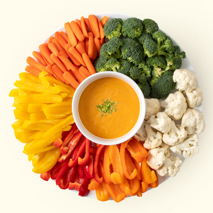 A bowl of Lowcountry dip on a platter ringed with carrots, peppers and broccoli.