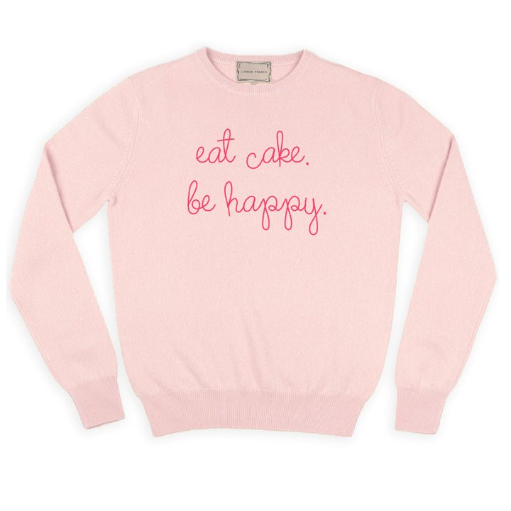 A pale pink cashmere sweater chain-stitched in bright pink with the words eat cake. be happy.